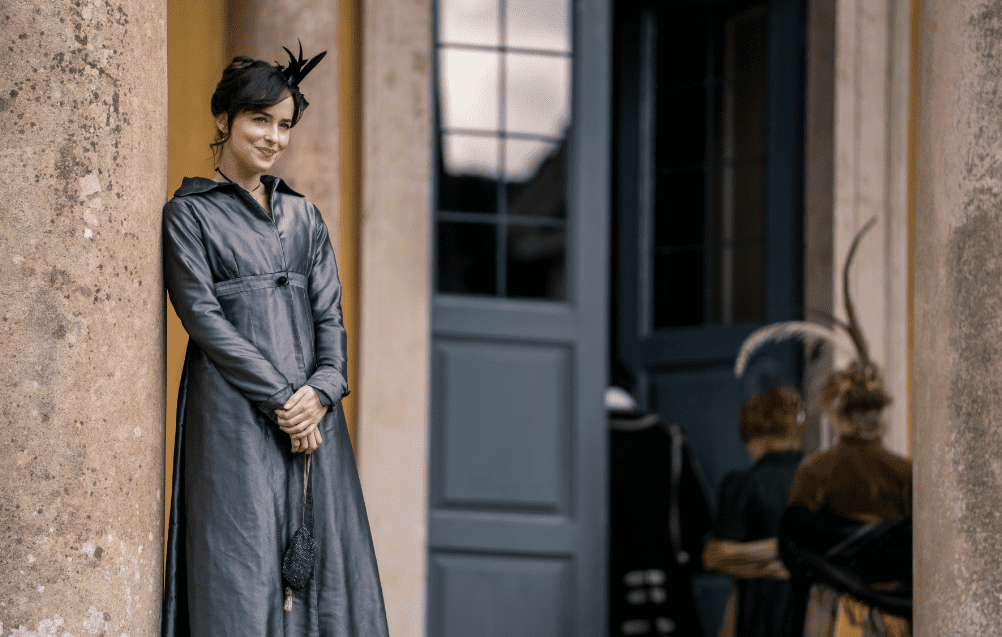 Dakota Johnson dressed in Victorian-era clothing with hands clasped in front